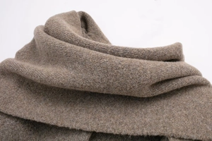 Macro shot of thick brown knitted fabric showing premium wool texture and soft drape