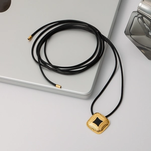 Square black enamel gold pendant necklace on laptop with perfume for urban style
