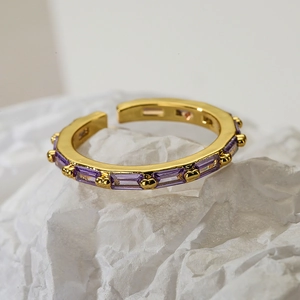 Minimalist adjustable gold ring with purple zircon baguette stones on textured background