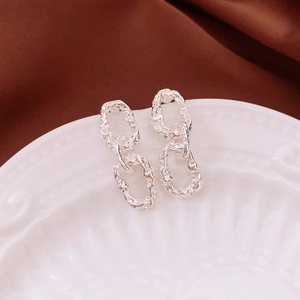 Macro view of silver vintage textured chain link earrings on a ceramic display