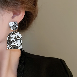 Detailed close-up of Pop Art face illustration earrings on a model in a modern style
