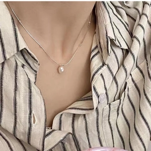 Detail of elegant silver snake chain featuring white pearl pendant on model neck