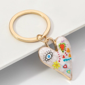 Détail d'un porte-clés cœur doré avec texture marbrée et motifs d'oeil porte-bonheur