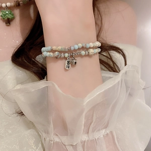 Double-layer ceramic beaded necklace with light blue marble stones and a bell pendant