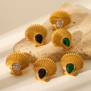 Detail of shell-shaped 18K gold earrings with white, black, and emerald green zircons