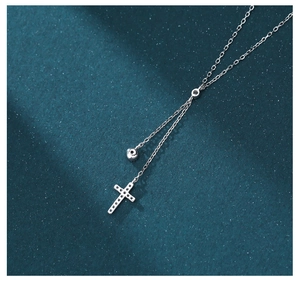 Close-up of S925 silver cross necklace with sparkling crystals on dark blue background