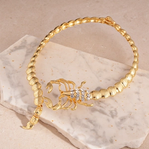 Vue détaillée du collier scorpion doré orné de strass brillants sur marbre blanc