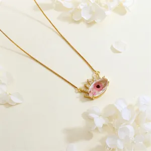 Detailed close-up of the gold-plated evil eye pendant with pink dried flowers and cubic zirconia
