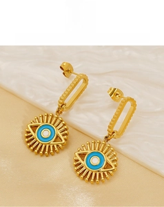 Detail of golden stainless steel evil eye drop earrings with blue enamel sun pendant