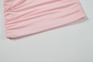 Detailansicht eines rosa Langarmkleids mit gerafftem Seitendesign und elastischem Stoff