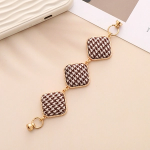 Detail of houndstooth fabric and metal alloy bracelet strap with magnetic clasp
