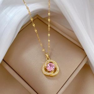 Close-up of golden necklace with pink gemstone pendant in beige jewelry box on silk