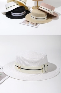 Détail d'un chapeau de paille à haut plat avec tissage texturé et logo M en métal doré