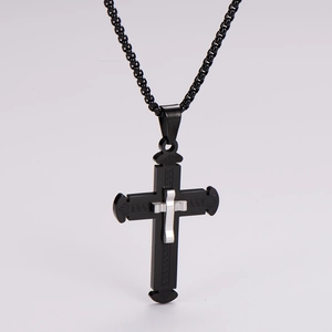 Detail of black cross pendant with engraved patterns and silver inlay on metal chain