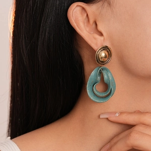 Detail of vintage teardrop earrings with teal enamel and gold flecks on a female model