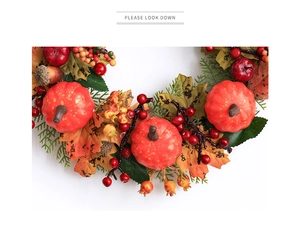 Close-up of fall wreath featuring orange pumpkins, red berries and dried maple leaves
