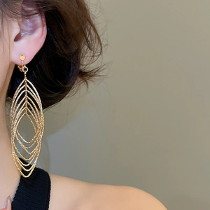 Detail view of large multi-layer hollow oval ear clips with golden sand textured finish