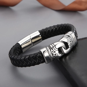 Macro shot of men's braided leather bracelet with engraved stainless steel tube and magnetic clasp