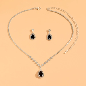 Close-up of silver necklace and earrings set with pear-shaped black zircons and crystals