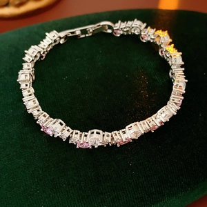 Detail of silver bracelet featuring pink and clear cubic zirconia on green velvet