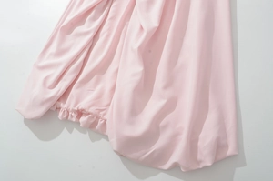 Gros plan détaillé du tissu rose de la robe montrant la texture et l'ourlet volanté