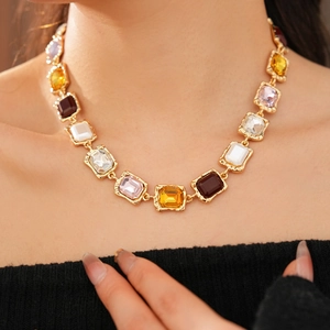 Detail of vintage gold necklace with multi-colored square gemstones on a model neck