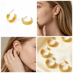 Macro view of gold C-shaped earrings with diamond pattern texture and 18k gold plating