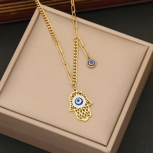 Macro detail of Hamsa hand pendant and blue evil eye charm on golden necklace