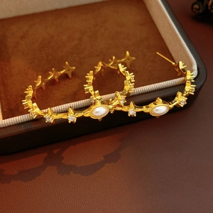 Detailed close-up of vintage gold star earrings with white pearls and micro-set diamonds
