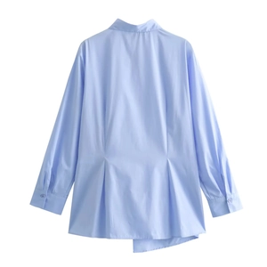 Rear view of light blue poplin shirt featuring waist pleats and asymmetric hemline