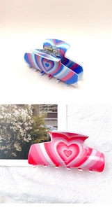 Close-up of colorful heart-shaped acrylic hair claws in blue and pink glaze finishes