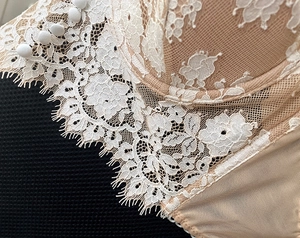 Detailed close-up of ivory eyelash lace and silk buttons on the back of the sexy lace bra