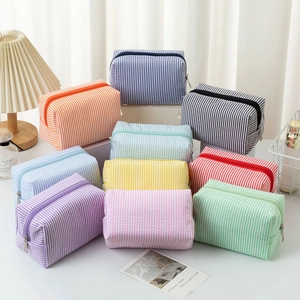 Detail showing various colors of striped seersucker makeup bags with metal zippers