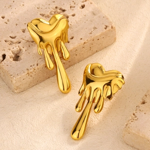 Detailed view of gold molten heart earrings with high-polish finish on travertine stone