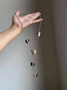 Detailed view of silver Y-shaped long necklace with five polished circular pendants