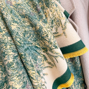 Macro shot of forest landscape print knit scarf with vibrant yellow tassel fringe detail
