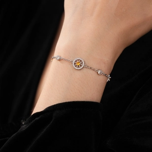 Macro detail of French style zircon starburst compass bracelet in silver and yellow