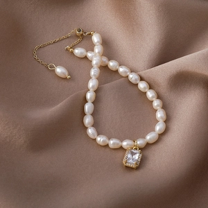 Macro detail of Baroque freshwater pearl bracelet with golden adjustable chain and zircon charm