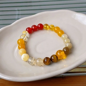 Detail of colorful gemstone beads bracelet with red agate and tiger eye in a ceramic tray