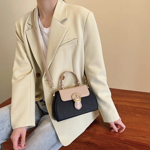 Close-up of stylish contrast color crossbody bag styled with a beige blazer for a modern look