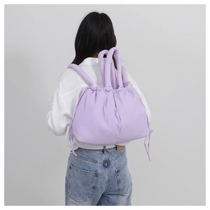 Detailed back view of a light purple quilted nylon drawstring tote bag worn by a model