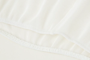 Macro shot of white mesh fabric texture and fine hem stitching on a V-neck blouse