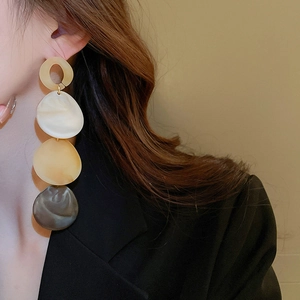 Detail view of long acrylic teardrop earrings with marble texture on female model