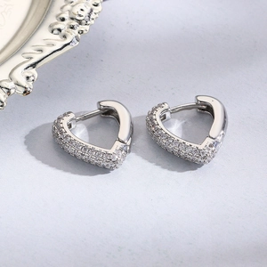 Macro shot of silver heart earrings with micro-pave cubic zirconia on gray textured base