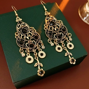 Detailed view of vintage gold earrings with hollow texture and black gemstone tassels