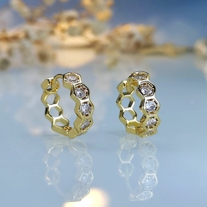 Macro shot of gold honeycomb earrings featuring white cubic zirconia and mirror reflections