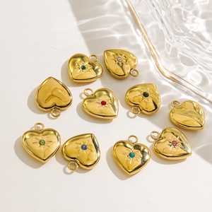Golden heart pendants with colorful crystals and star engraving on white background