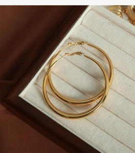Gros plan de boucles d'oreilles créoles dorées épaisses avec finition polie brillante