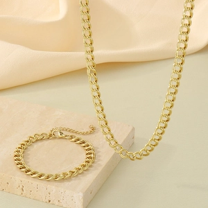 Detail of gold double-circle link chain necklace and bracelet on marble stone base