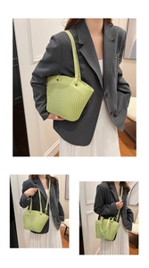Detail shot of light green pleated bucket bag with dual handles and golden hardware